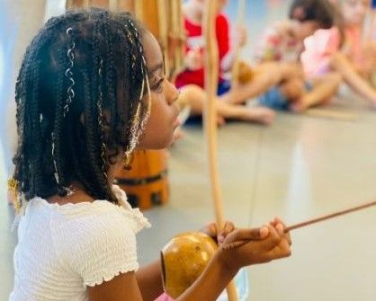 Child holding a wooden instrument